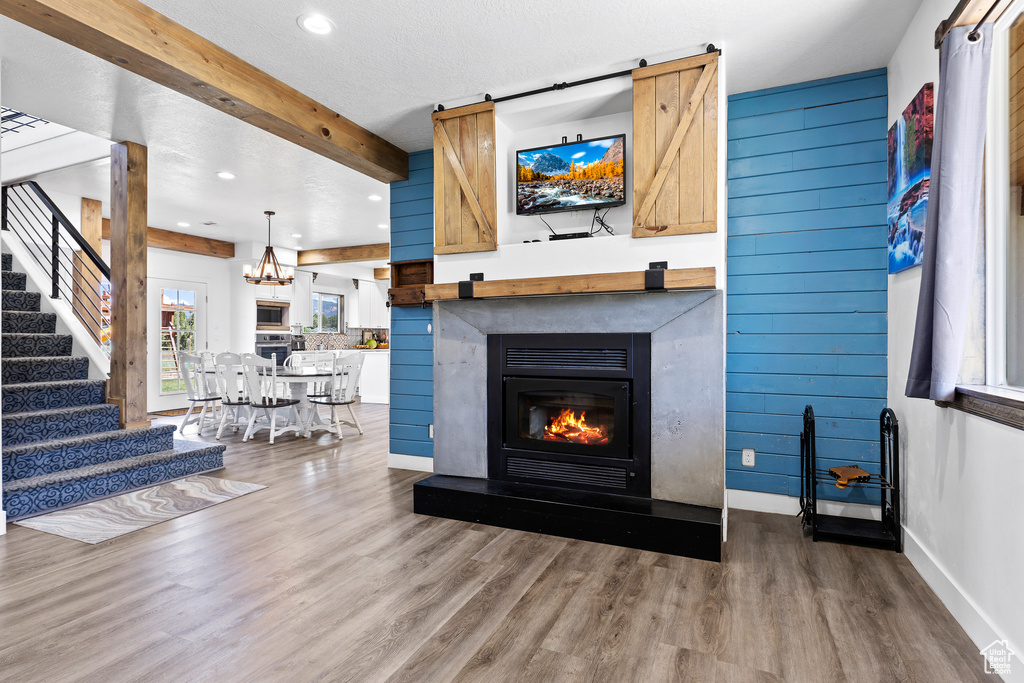 Living area with wood finished floors, a glass covered fireplace, recessed lighting, baseboards, and stairs