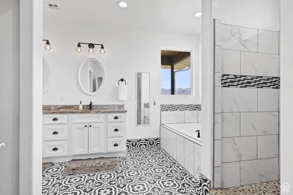 Full bathroom featuring a bath, vanity, tiled shower, and recessed lighting
