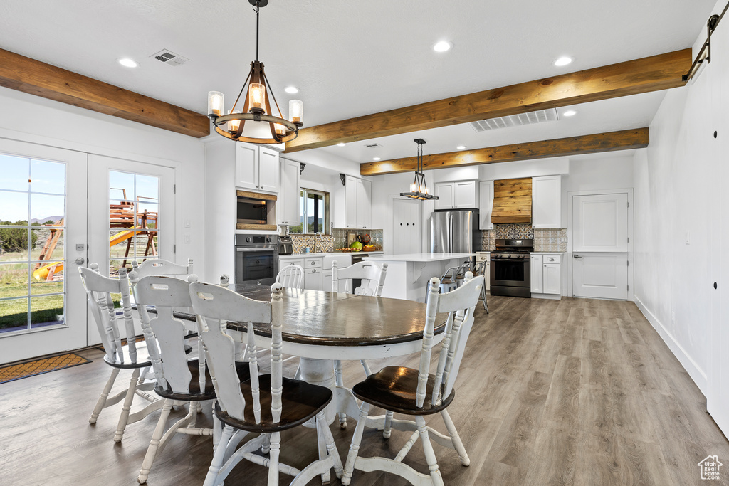 Dining room featuring beam ceiling, recessed lighting, plenty of natural light, a chandelier, and light wood-type flooring