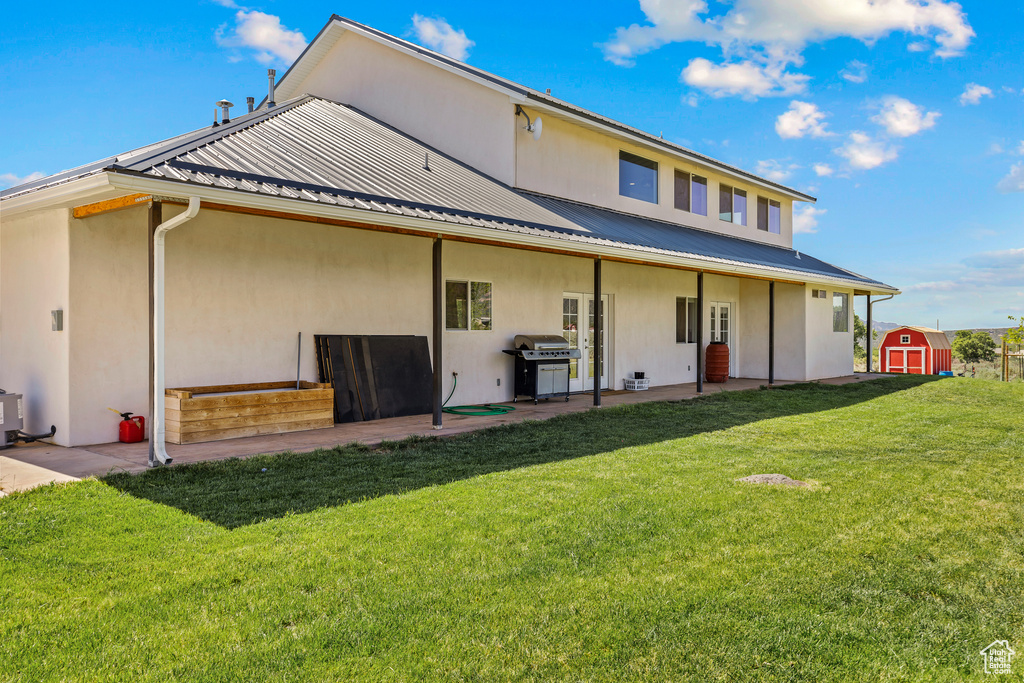 Back of house featuring a yard, a patio area, metal roof, and stucco siding