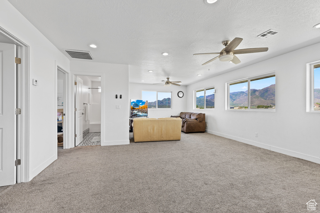 Carpeted living area with ceiling fan, recessed lighting, a textured ceiling, and baseboards