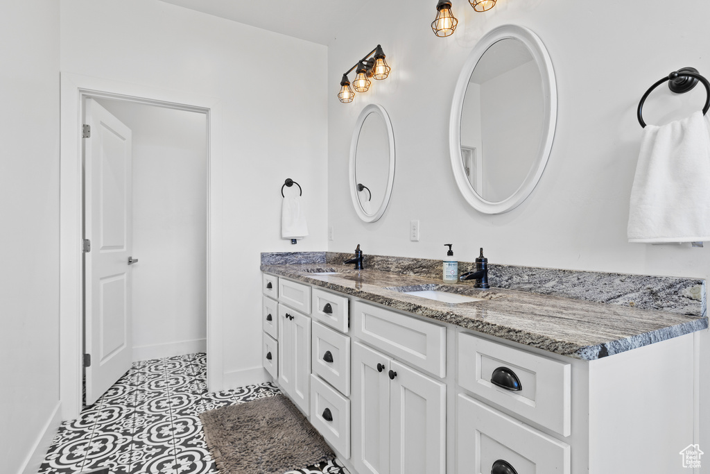 Bathroom featuring double vanity, baseboards, and tile patterned floors