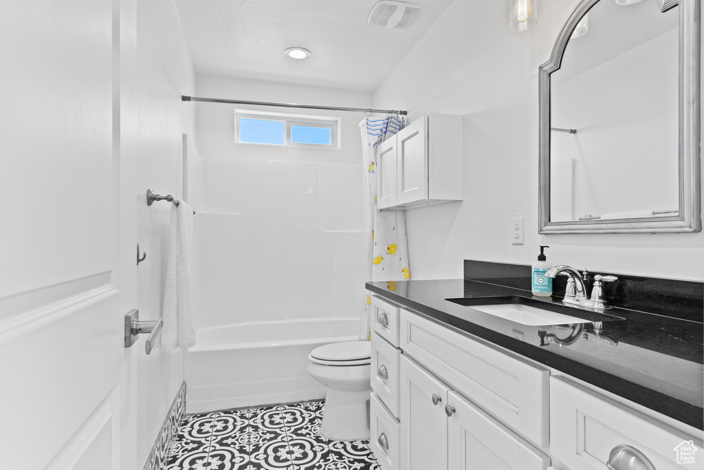 Full bath featuring vanity, shower / bath combo with shower curtain, toilet, and tile patterned flooring