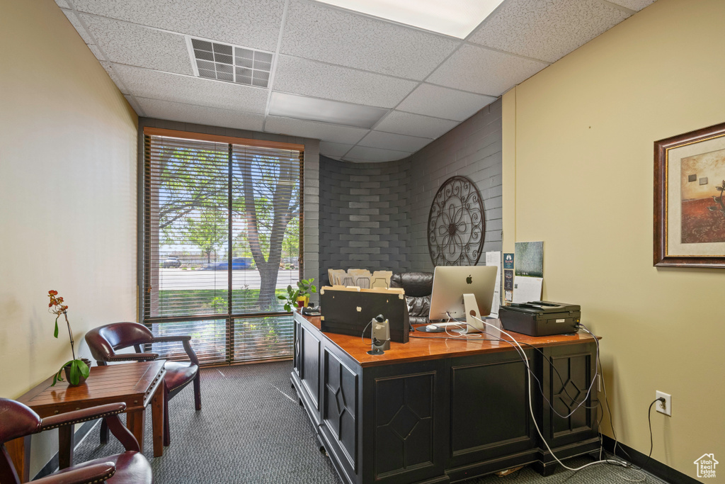Office space featuring dark carpet and a paneled ceiling