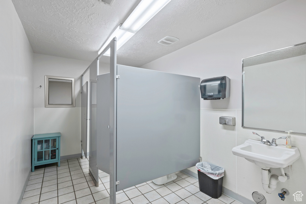 Bathroom with a textured ceiling, baseboards, and tile patterned floors