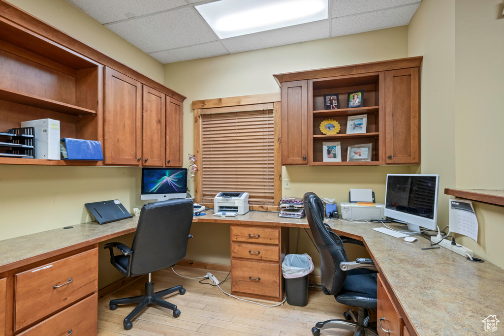 Office featuring built in desk, a drop ceiling, and light wood-style flooring