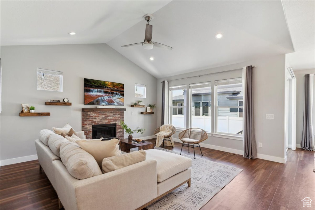 Living room with lofted ceiling, ceiling fan, baseboards, a fireplace, and dark wood-style floors
