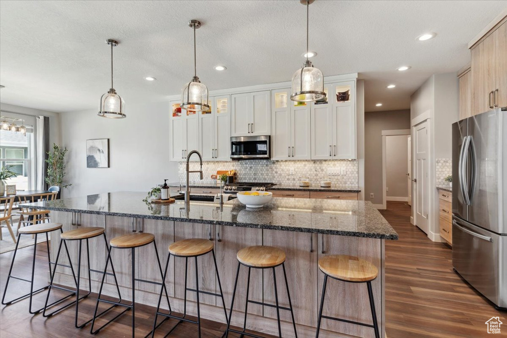 Kitchen with stainless steel appliances, decorative backsplash, dark wood-style floors, a breakfast bar area, and recessed lighting