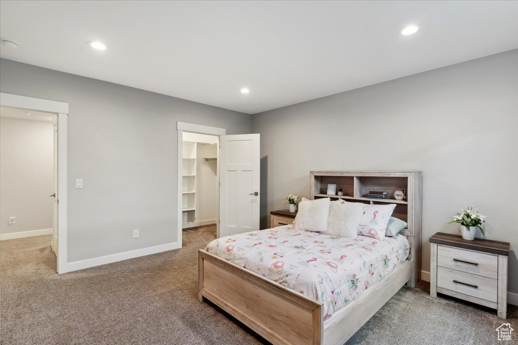 Carpeted bedroom with baseboards, a walk in closet, and recessed lighting