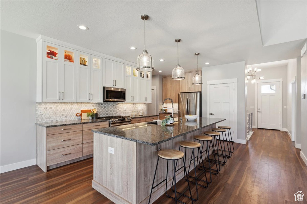 Kitchen featuring appliances with stainless steel finishes, a sink, baseboards, backsplash, and dark wood finished floors