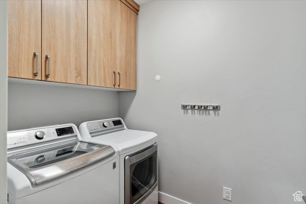 Laundry area with separate washer and dryer, cabinet space, and baseboards
