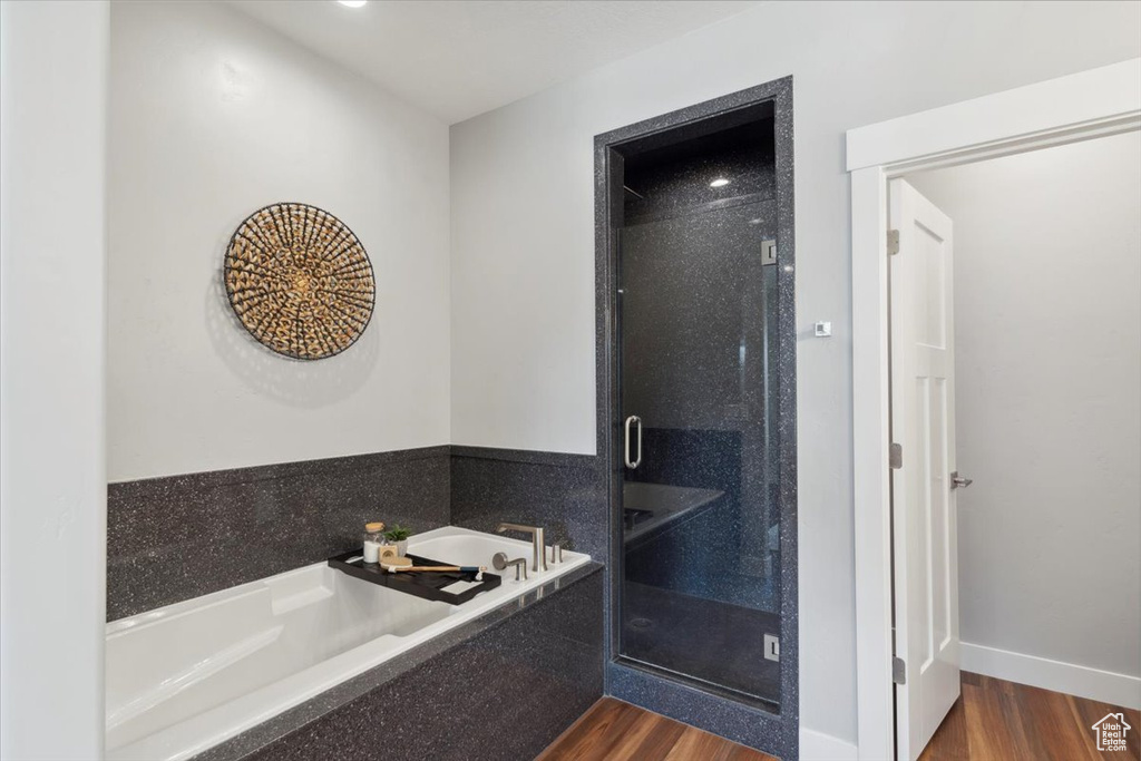 Bathroom featuring wood finished floors, a stall shower, and a bath