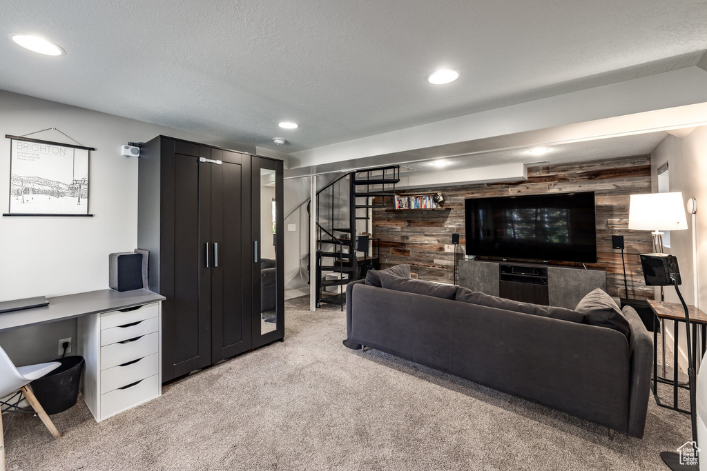 Living area with light carpet, stairs, wooden walls, and recessed lighting