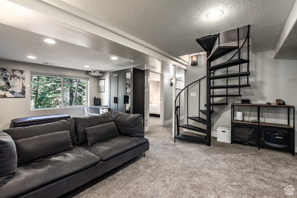 Carpeted living area with a textured ceiling, stairs, and recessed lighting