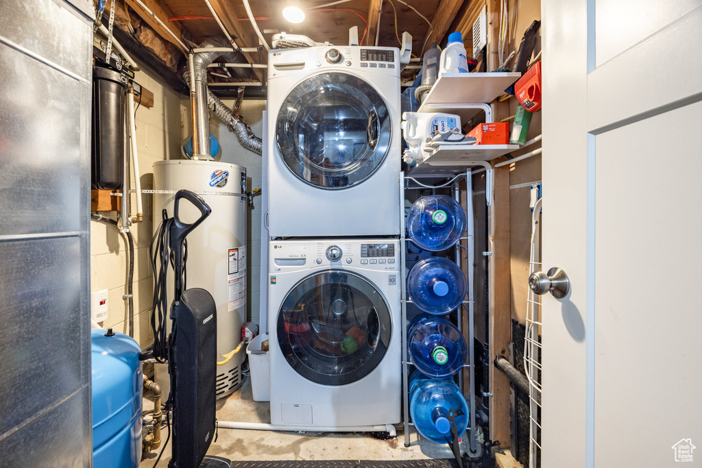 Washroom featuring estacked washer and dryer, gas water heater, and concrete block wall