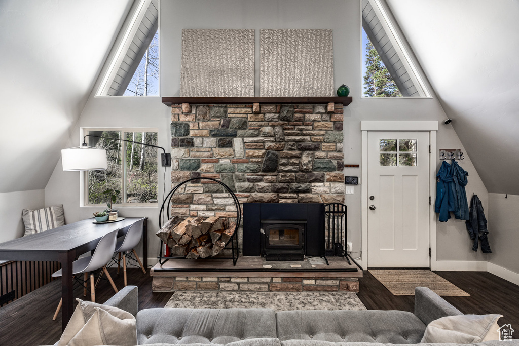 Living area featuring wood finished floors, a wood stove, baseboards, and high vaulted ceiling