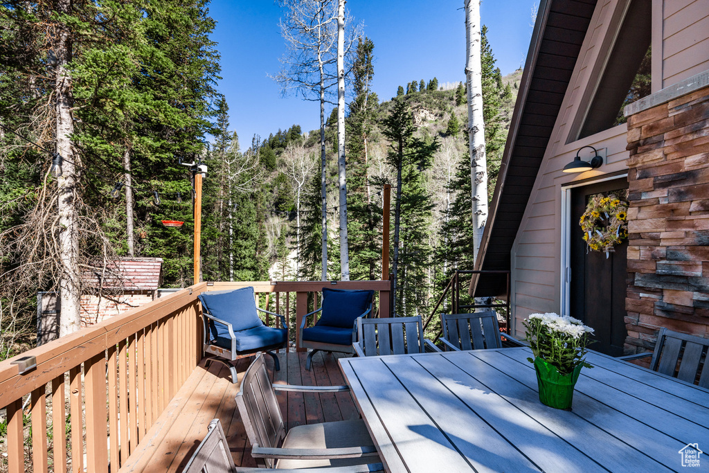 Wooden deck with outdoor dining area and a wooded view