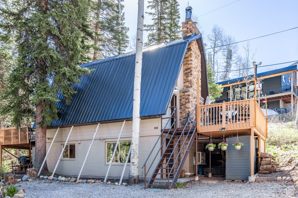 Back of property featuring a chimney, metal roof, stairway, and a deck