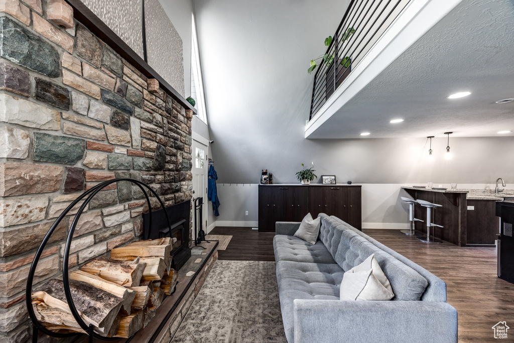 Living room with baseboards, wet bar, dark wood-style flooring, recessed lighting, and a high ceiling