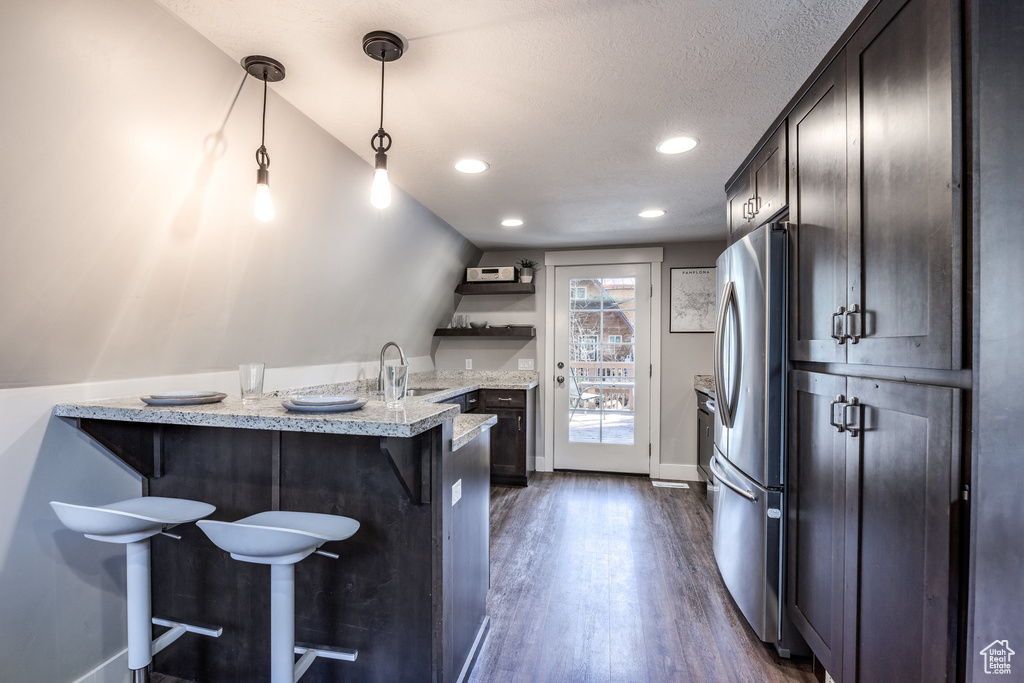 Kitchen with open shelves, a peninsula, dark wood-type flooring, a breakfast bar area, and a sink