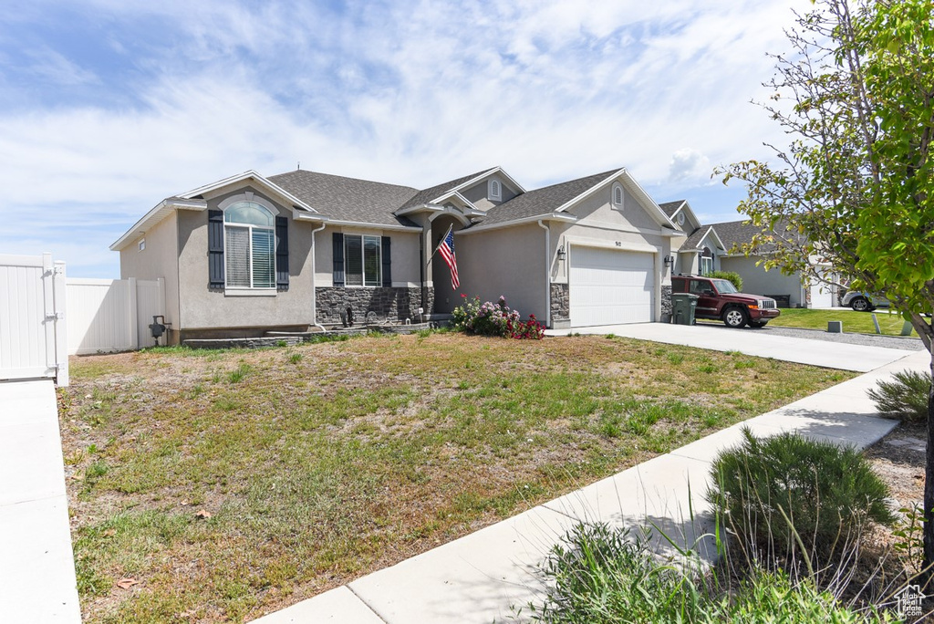 View of front facade with stucco siding, an attached garage, driveway, and a gate
