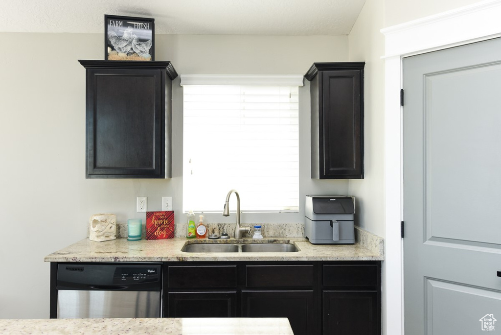 Kitchen featuring dishwasher, a sink, healthy amount of natural light, and dark cabinetry