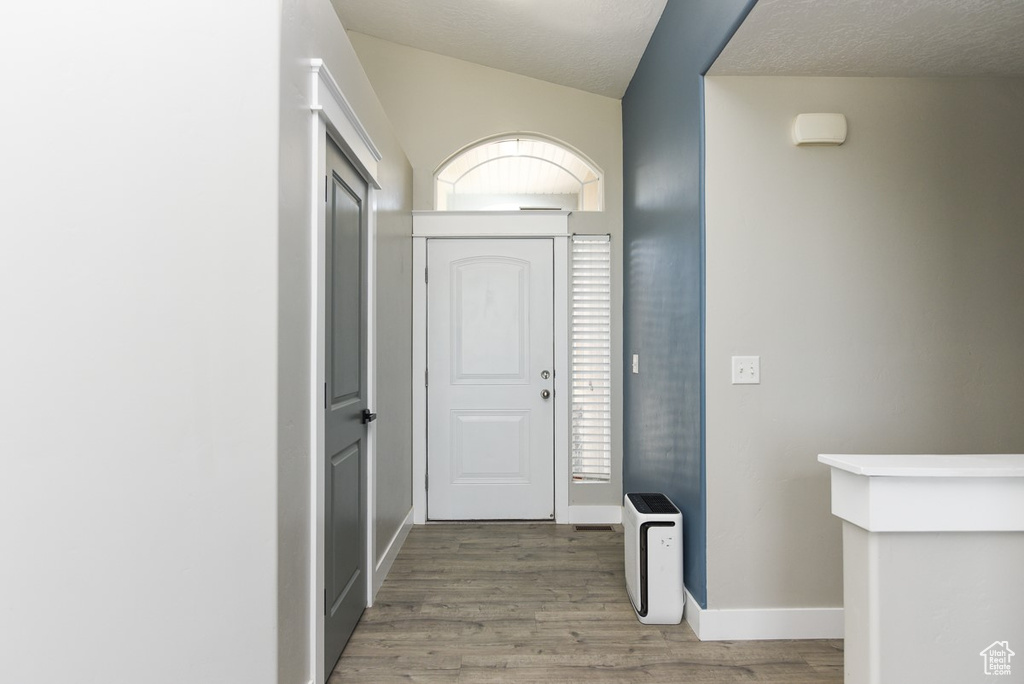 Foyer entrance featuring wood finished floors, baseboards, and lofted ceiling