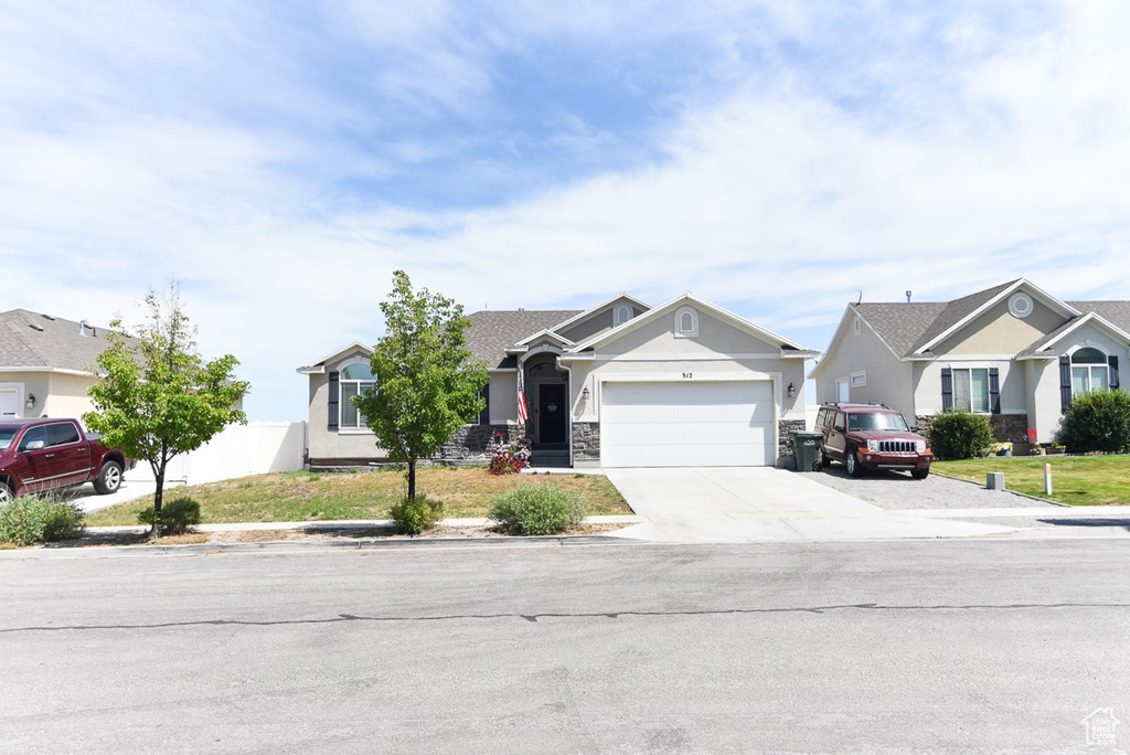 View of front facade with stucco siding, a garage, driveway, and a residential view