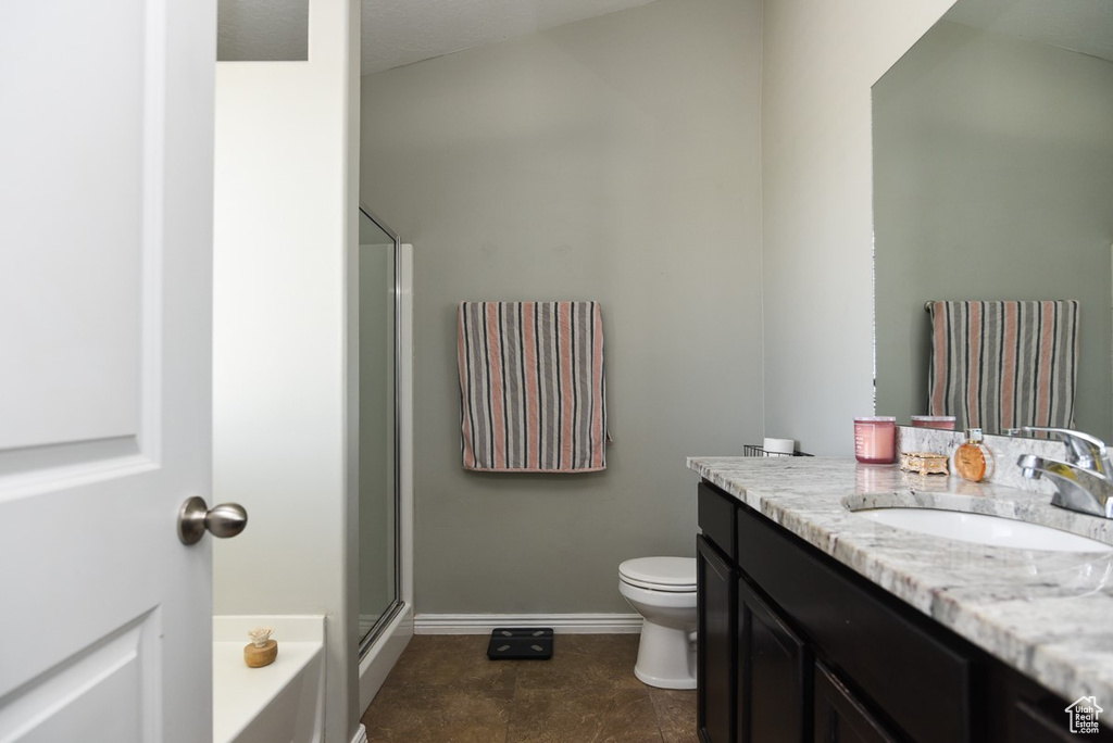 Bathroom featuring vanity, toilet, a shower with shower door, baseboards, and a bath