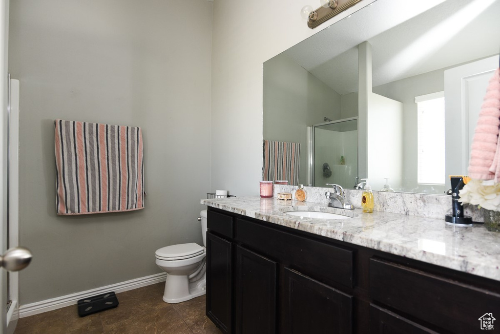 Bathroom with a shower stall, vanity, toilet, and baseboards