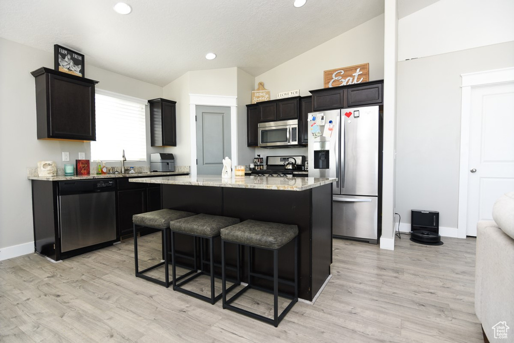 Kitchen featuring stainless steel appliances, recessed lighting, a kitchen island, light wood-type flooring, and a kitchen breakfast bar