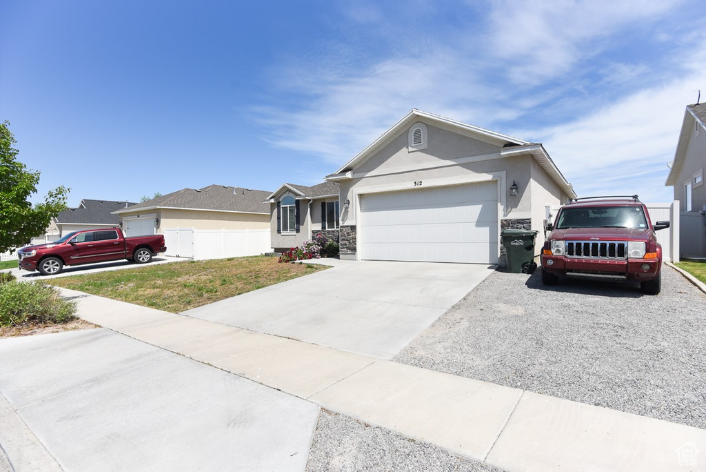 Single story home featuring stucco siding, a garage, driveway, and stone siding