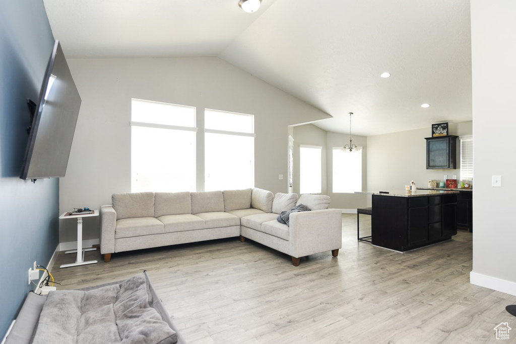 Living room featuring a chandelier, light wood-style flooring, vaulted ceiling, baseboards, and recessed lighting