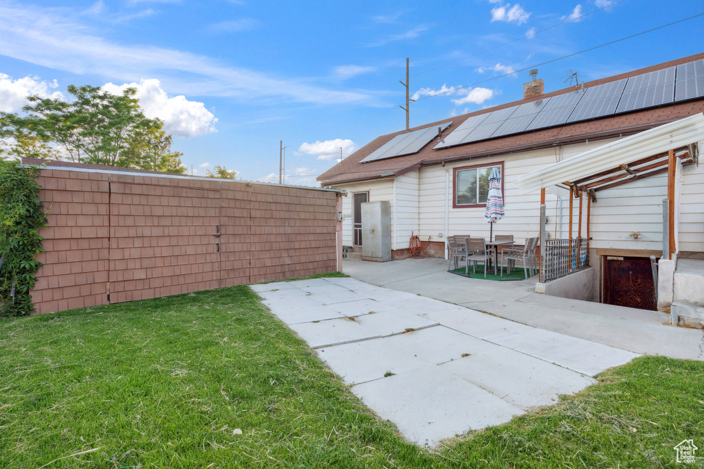 Back of house featuring roof mounted solar panels, a patio, a chimney, and a pergola