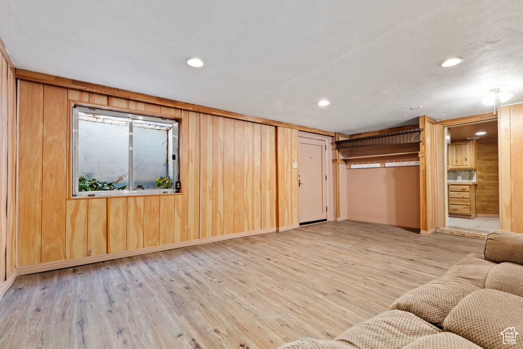 Unfurnished living room with wood finished floors, recessed lighting, wood walls, and baseboards