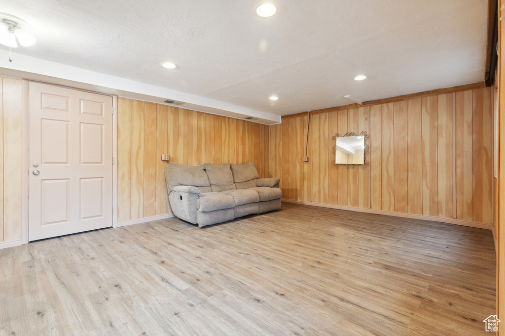 Unfurnished living room with wood finished floors, wooden walls, recessed lighting, and baseboards