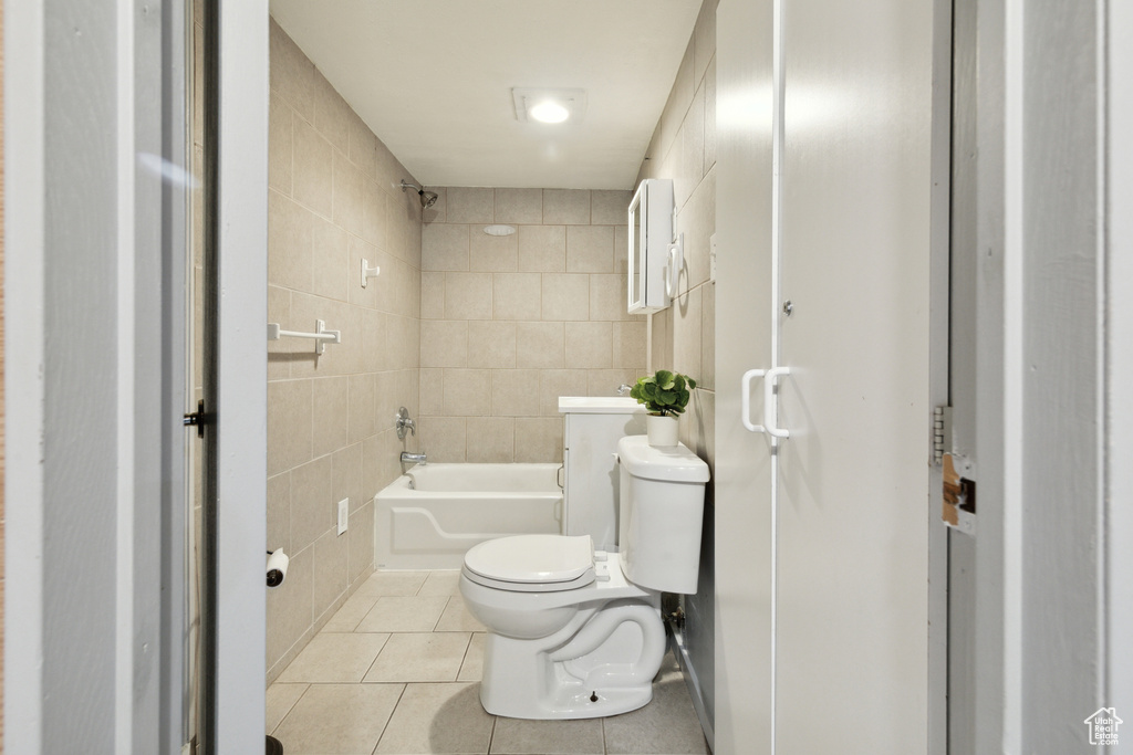 Bathroom with tile walls, toilet, tile patterned floors, and shower / bathtub combination