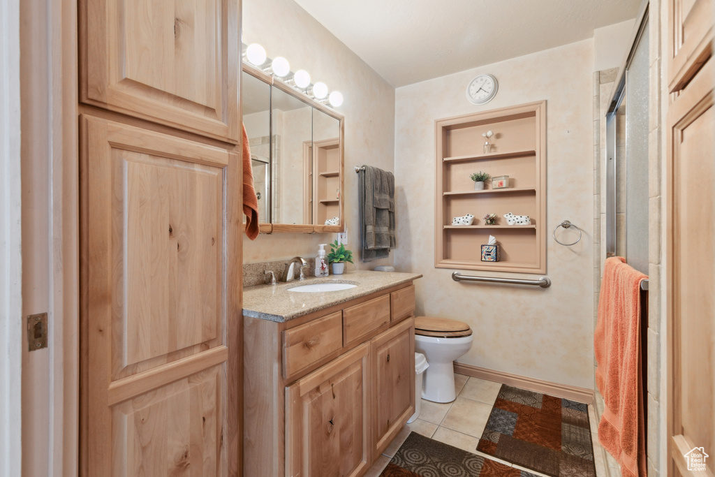 Bathroom featuring vanity, an enclosed shower, toilet, and tile patterned floors