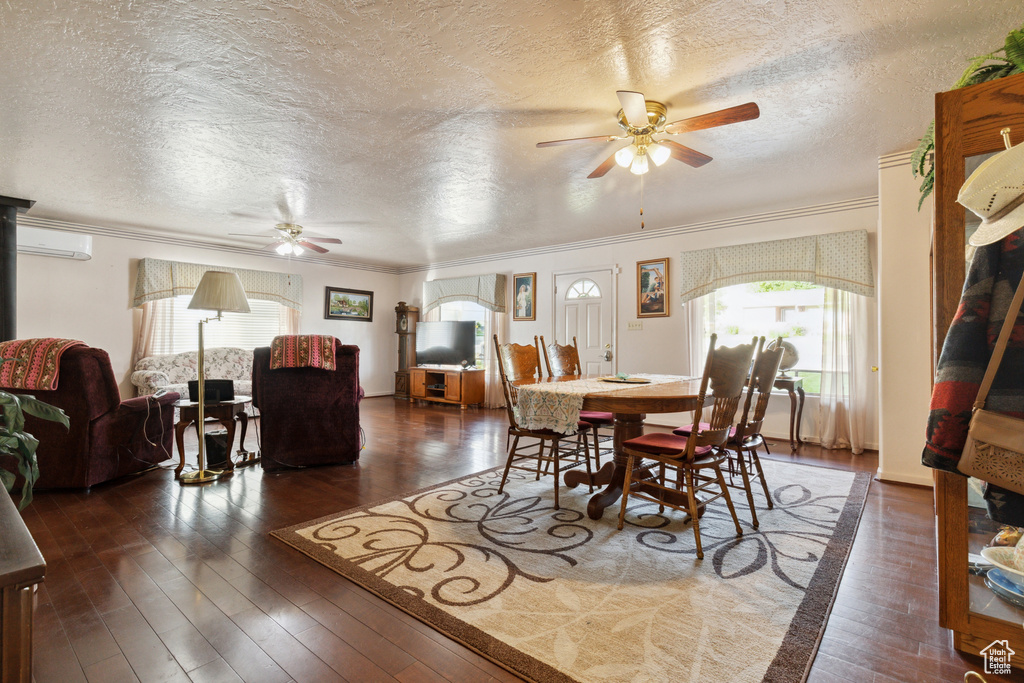 Dining area featuring a ceiling fan, a textured ceiling, ornamental molding, wood-type flooring, and a wall unit AC