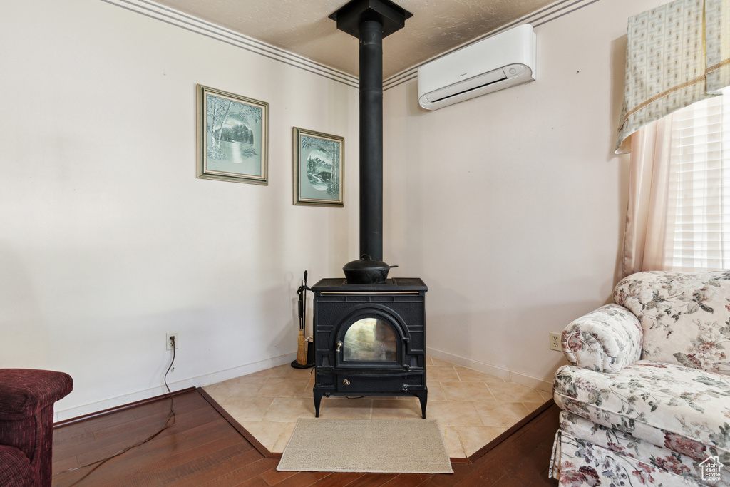 Detailed view of an AC wall unit, a wood stove, wood finished floors, and crown molding