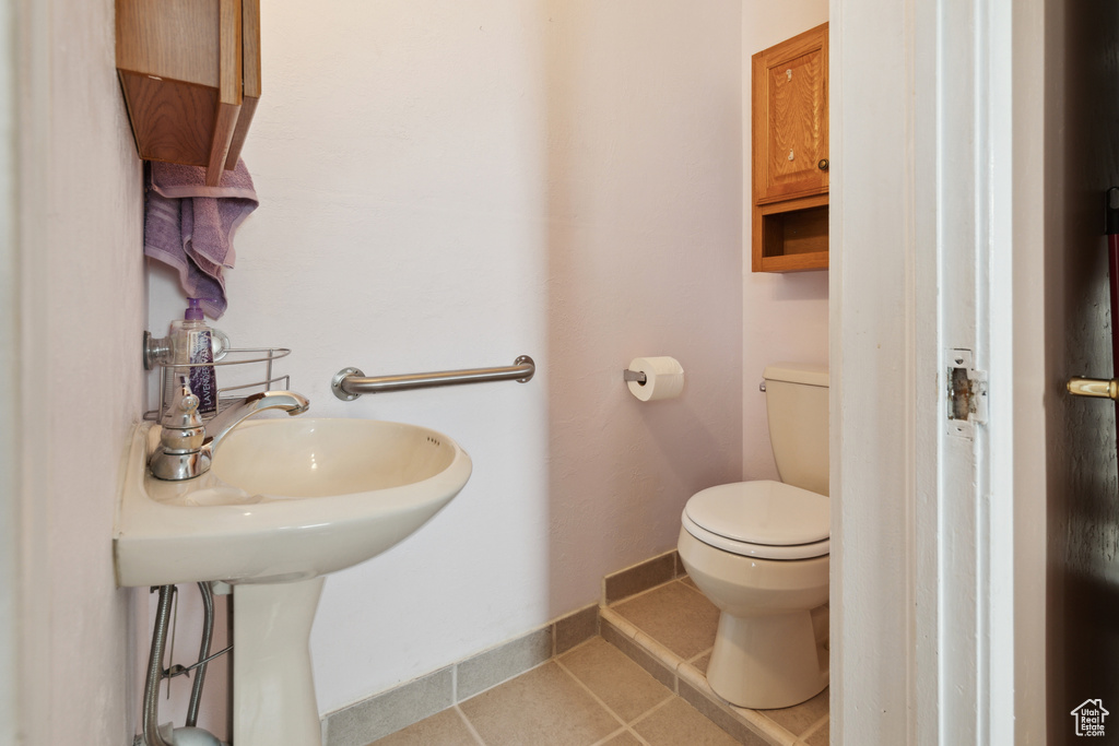 Half bathroom featuring toilet, tile patterned floors, and baseboards