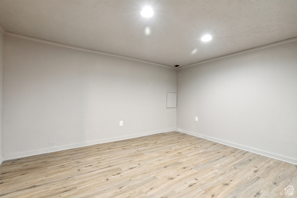 Spare room featuring light wood finished floors, baseboards, recessed lighting, and ornamental molding
