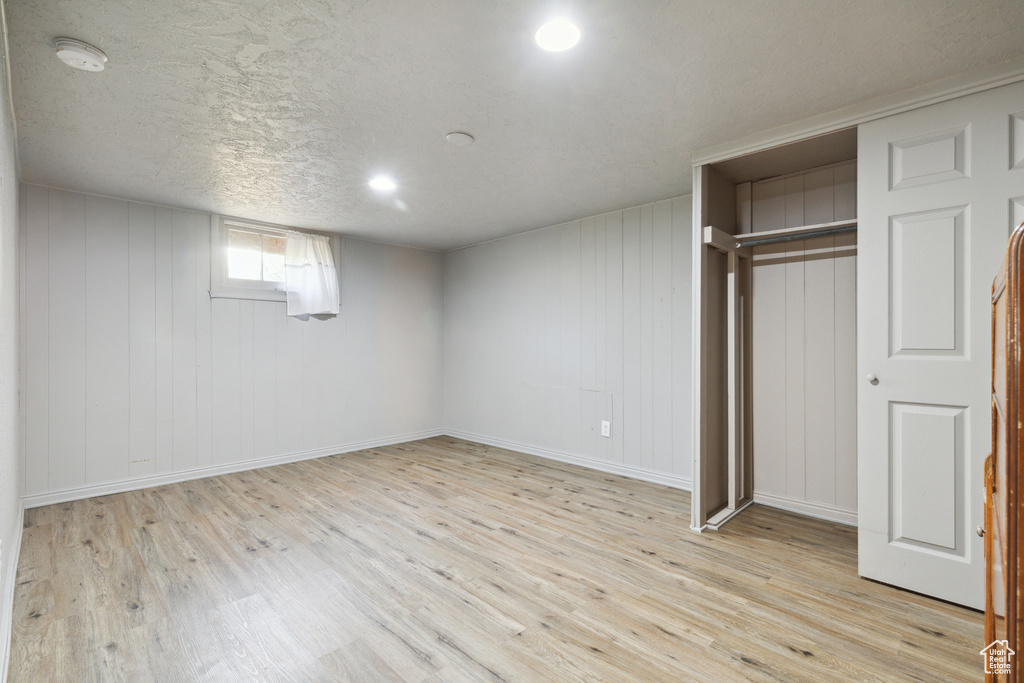 Unfurnished bedroom featuring light wood-style flooring, a closet, and baseboards