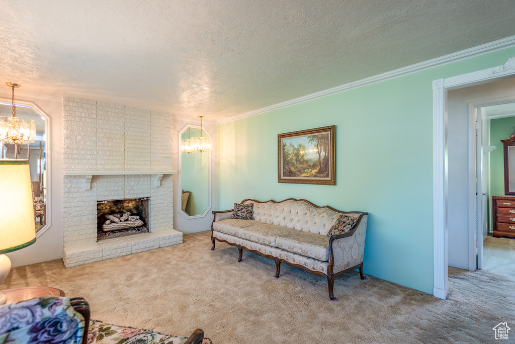 Carpeted living room with a chandelier, a textured ceiling, a brick fireplace, and crown molding