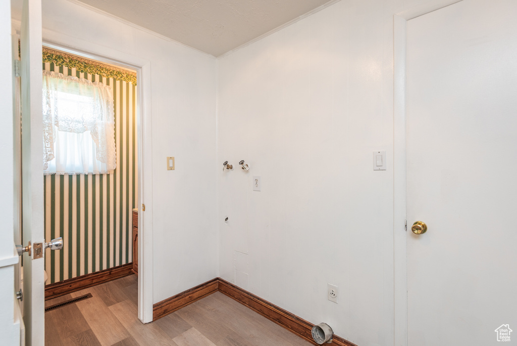 Washroom featuring light wood-type flooring, electric dryer hookup, ornamental molding, and baseboards