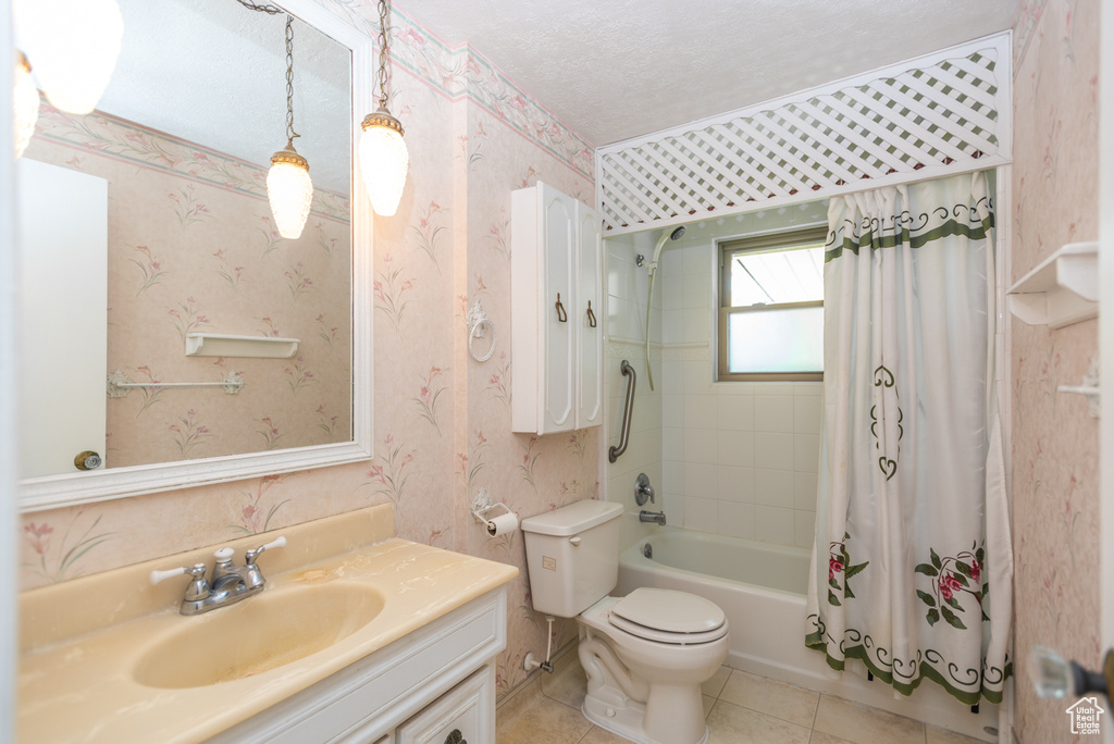 Bathroom with wallpapered walls, vanity, shower / tub combo with curtain, toilet, and tile patterned flooring