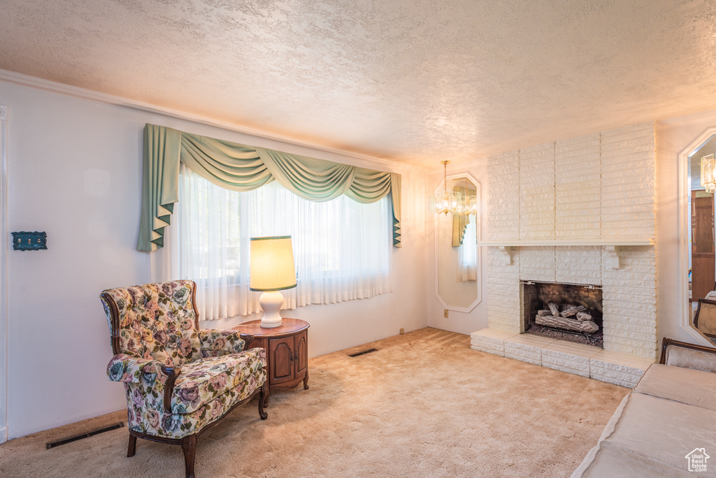Carpeted living room with a textured ceiling, healthy amount of natural light, a chandelier, and a brick fireplace