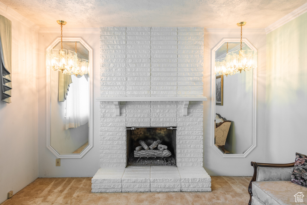Carpeted living area featuring a chandelier, a brick fireplace, a textured ceiling, and ornamental molding