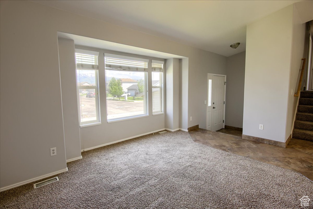 Carpeted spare room featuring stairs and baseboards