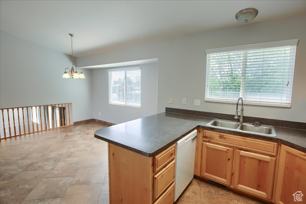 Kitchen featuring white dishwasher, a sink, a chandelier, dark countertops, and a peninsula